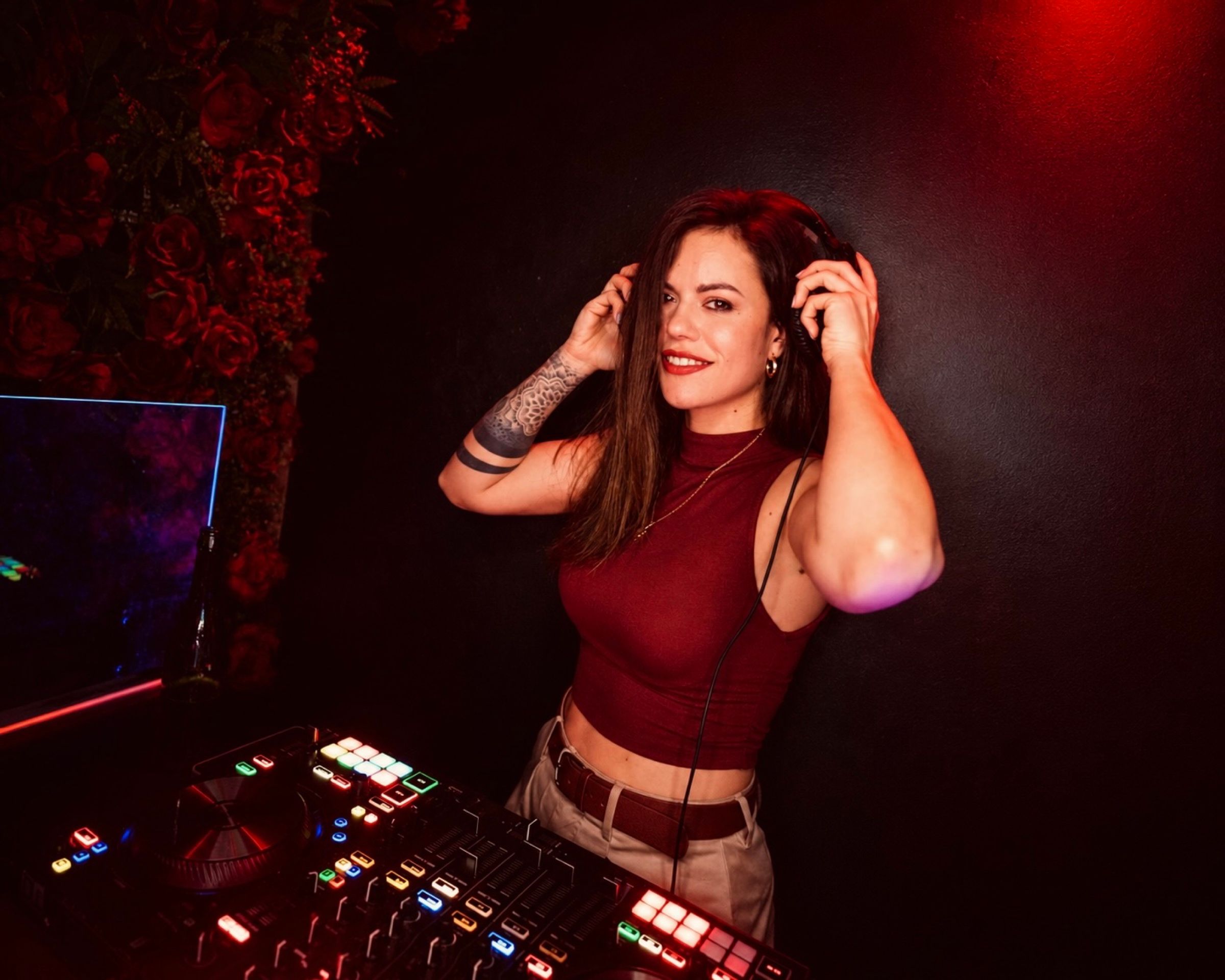 Orlean B sonriendo con auriculares frente a una pared de rosas